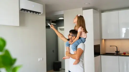 father carrying his daughter while adjusting the AC